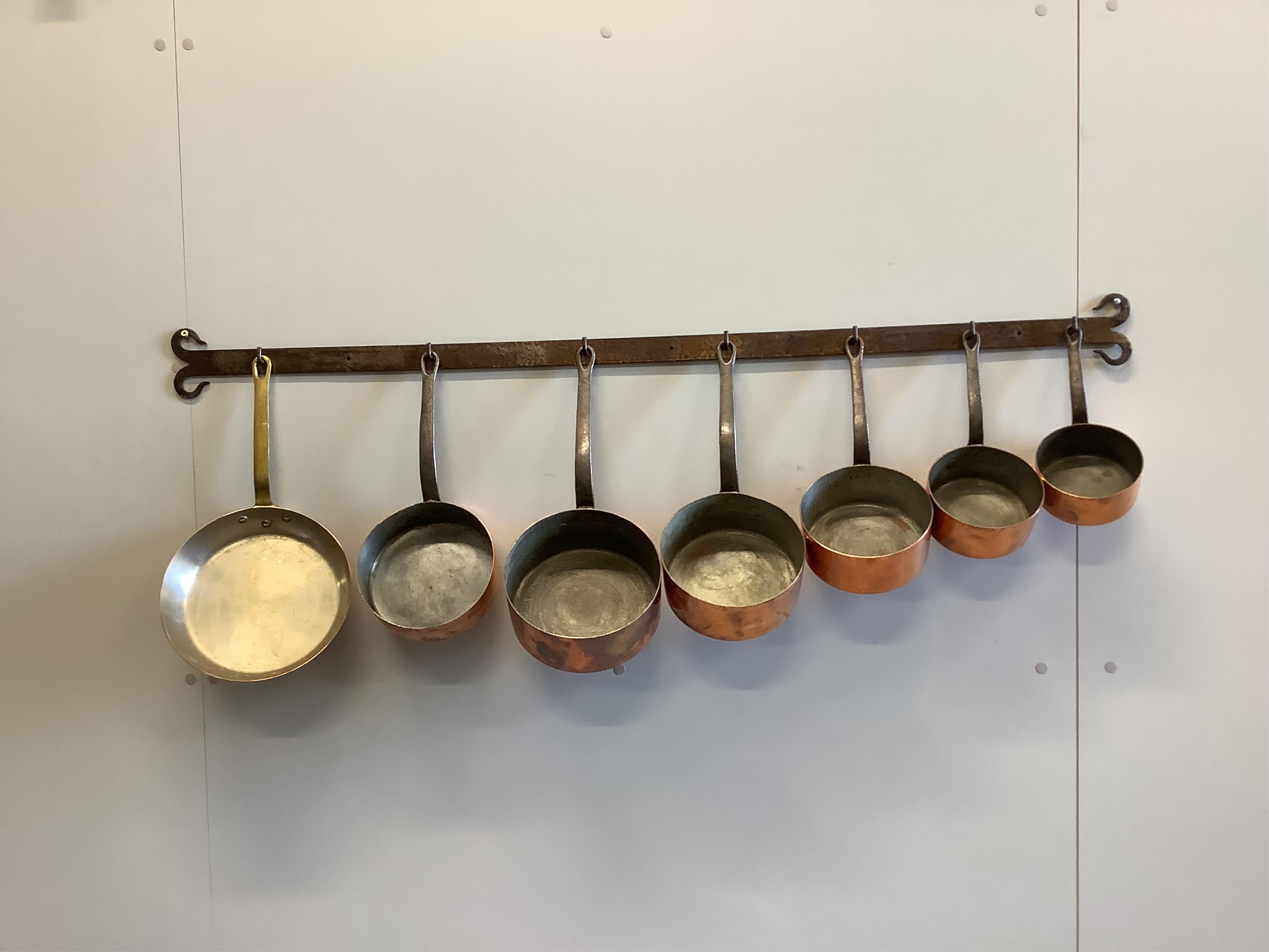 A graduated set of five French copper and wrought iron saucepans together with two further pans, larger diameter 24cm with wrought iron hanging rack, length 130cm. Condition - fair